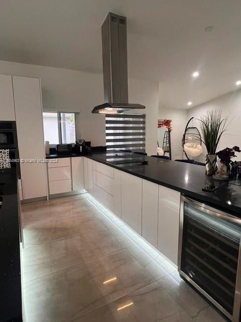 kitchen featuring wall chimney exhaust hood, black appliances, white cabinetry, and wine cooler