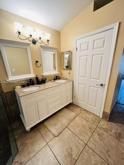 bathroom featuring vanity, vaulted ceiling, and tile patterned flooring