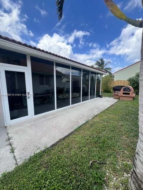 back of property featuring a yard and a sunroom