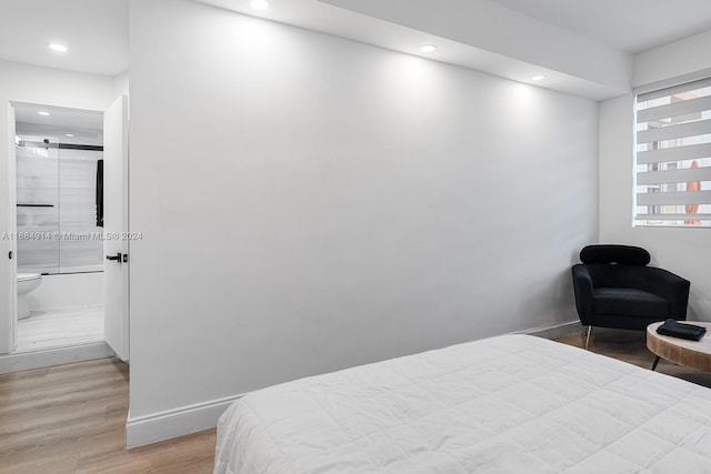 bedroom with light hardwood / wood-style flooring and ensuite bath