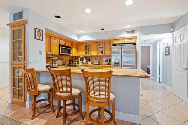 15442 Kippford Ct, Miami Lakes, FL 33014 - kitchen with light stone counters, stainless steel appliances, light tile patterned floors, backsplash, and visible vents