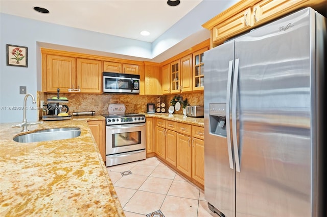 kitchen with tasteful backsplash, appliances with stainless steel finishes, sink, light stone counters, and light tile patterned floors