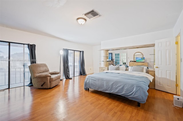 bedroom with access to outside, wood-type flooring, and multiple windows