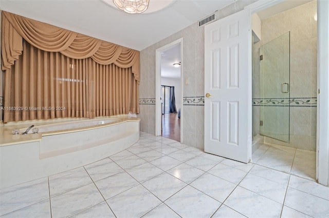 bathroom with shower with separate bathtub, tile patterned floors, and tile walls