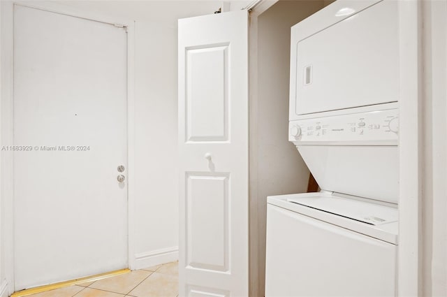 clothes washing area with light tile patterned floors and stacked washer and dryer