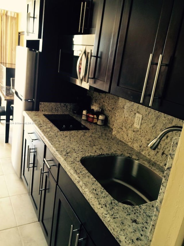 kitchen with tasteful backsplash, black electric cooktop, white fridge, light stone counters, and light tile patterned floors