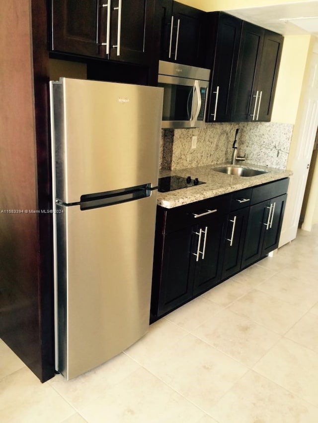 kitchen with decorative backsplash, stainless steel appliances, sink, light tile patterned floors, and light stone counters