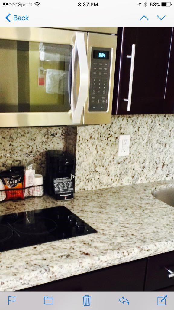 kitchen featuring light stone countertops, black electric stovetop, tasteful backsplash, and dark brown cabinets