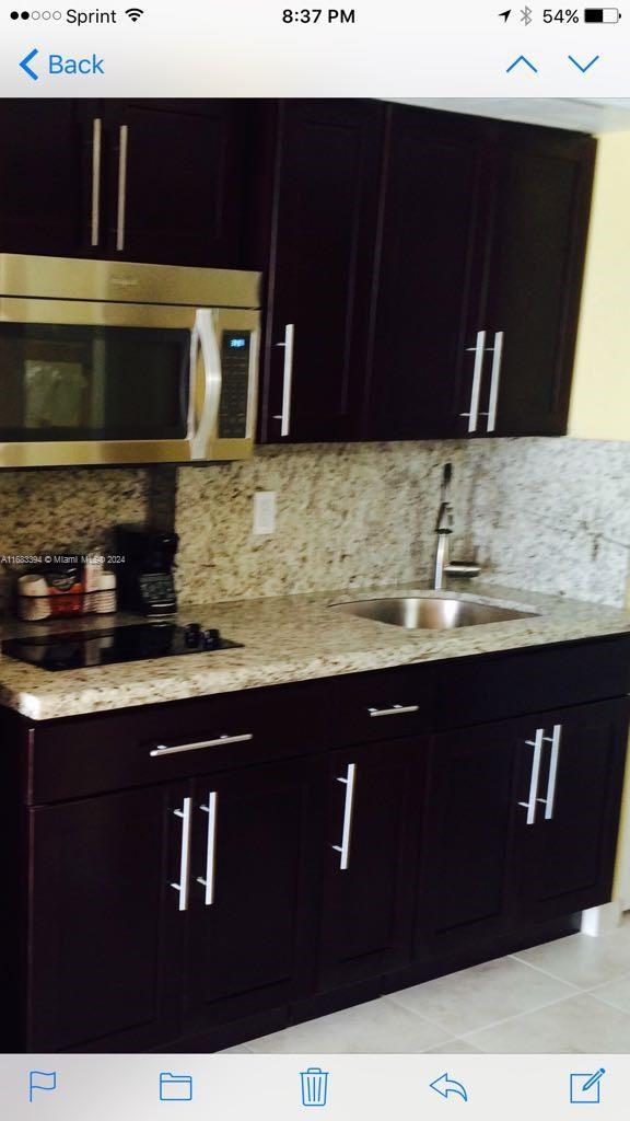 kitchen featuring tasteful backsplash, sink, dark brown cabinets, black electric cooktop, and light tile patterned floors