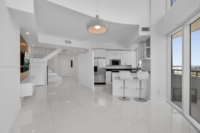 kitchen with white cabinets, light tile patterned floors, stainless steel appliances, and a breakfast bar area