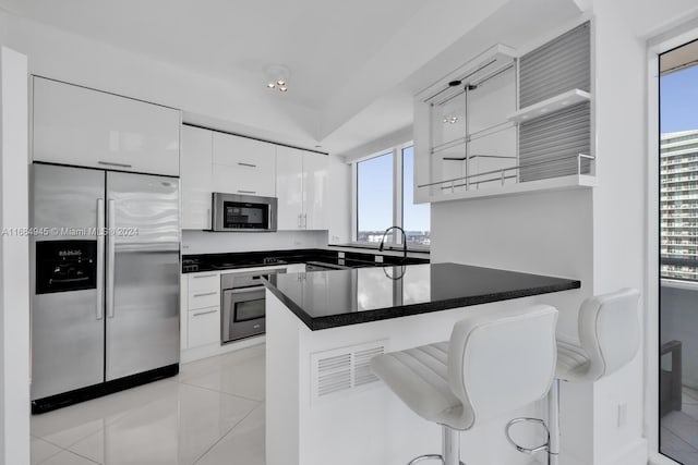 kitchen featuring white cabinets, a breakfast bar, a healthy amount of sunlight, and stainless steel appliances