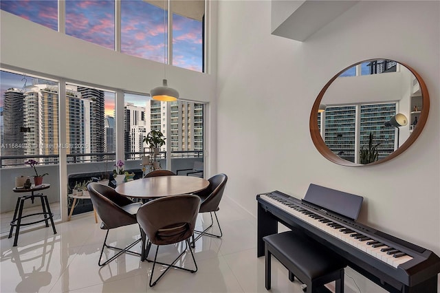 dining area with a towering ceiling, a view of city, and light tile patterned flooring