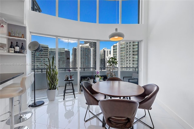 dining room with plenty of natural light, a high ceiling, baseboards, and a city view