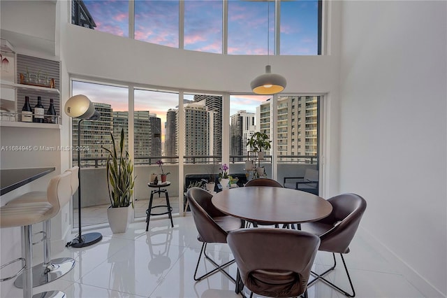 dining space featuring a high ceiling, baseboards, and a city view