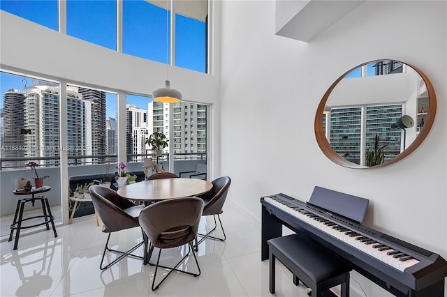 dining area with light tile patterned floors, a towering ceiling, and a city view