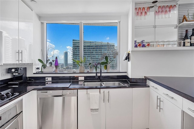 kitchen with stainless steel appliances, a sink, white cabinets, a view of city, and dark countertops