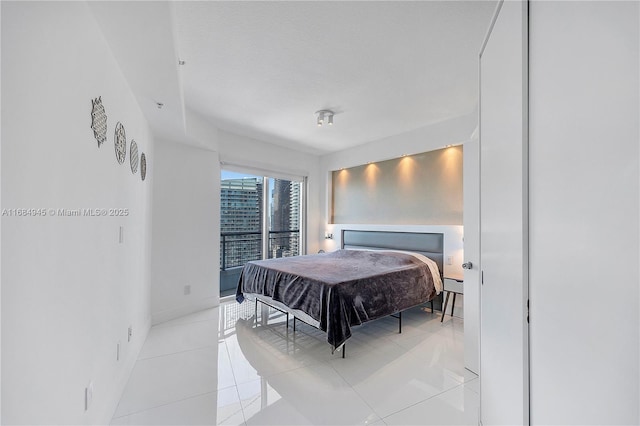 bedroom with light tile patterned floors, a city view, and baseboards