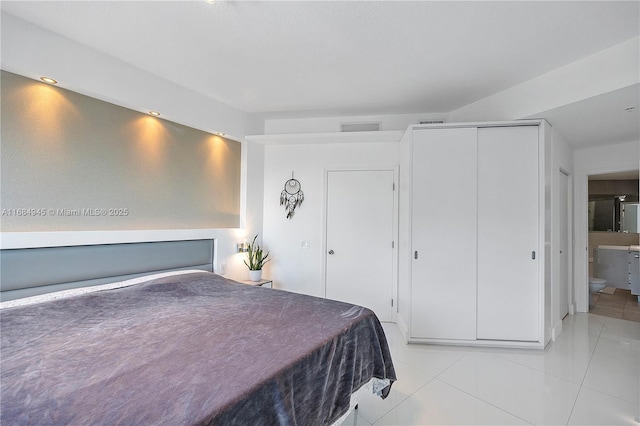 bedroom with a closet, light tile patterned flooring, and visible vents