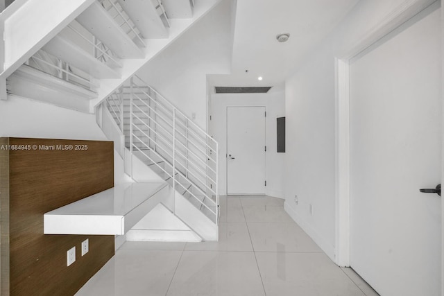 stairs with baseboards and tile patterned floors