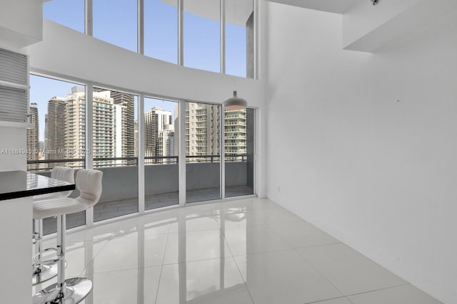 interior space with a towering ceiling, a city view, and tile patterned floors