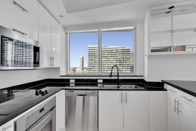 kitchen with a city view, a sink, white cabinets, appliances with stainless steel finishes, and dark countertops