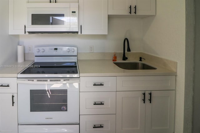 kitchen featuring white appliances, white cabinetry, and sink