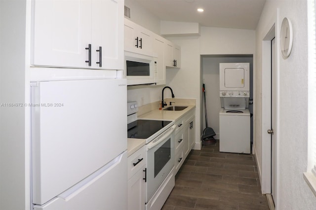 kitchen with white appliances, white cabinets, sink, dark hardwood / wood-style floors, and stacked washer / dryer