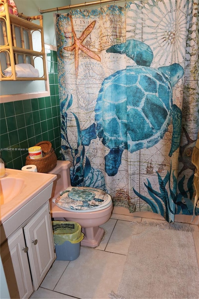 bathroom featuring curtained shower, toilet, tile patterned floors, tile walls, and vanity