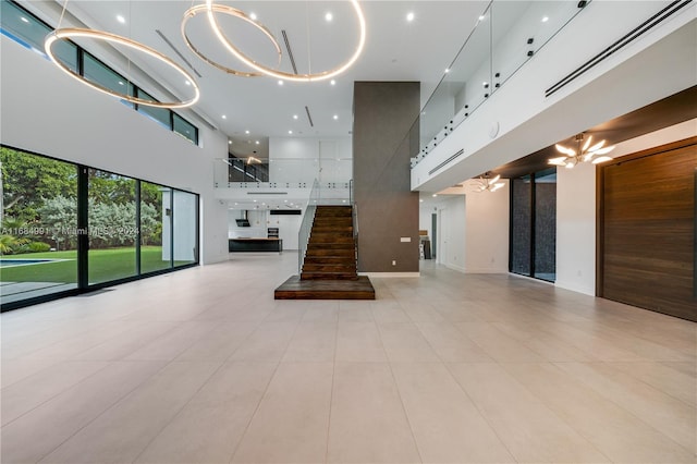 unfurnished living room featuring a towering ceiling, light tile patterned floors, and a chandelier