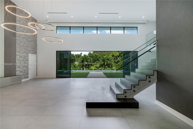 stairway with a wealth of natural light, a towering ceiling, and a notable chandelier