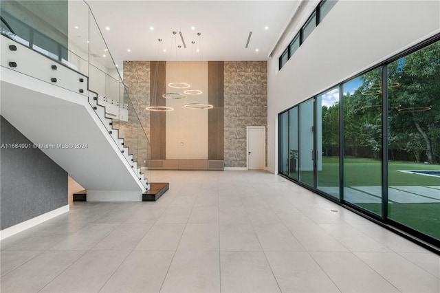 hall featuring a towering ceiling and light tile patterned floors