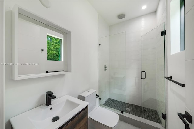 bathroom with vanity, a shower with shower door, and toilet