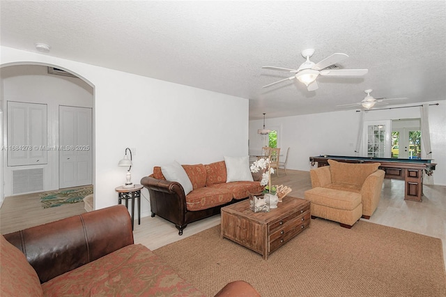 living room with a textured ceiling, ceiling fan, pool table, and light wood-type flooring