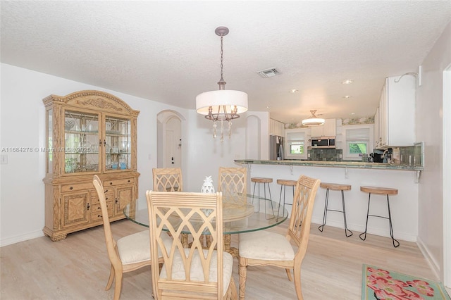 dining room featuring a notable chandelier, a textured ceiling, and light hardwood / wood-style flooring