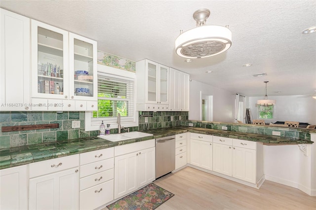 kitchen with decorative light fixtures, dishwasher, sink, and white cabinetry