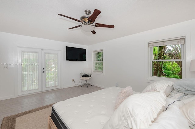 bedroom featuring ceiling fan, light tile patterned floors, access to outside, and multiple windows