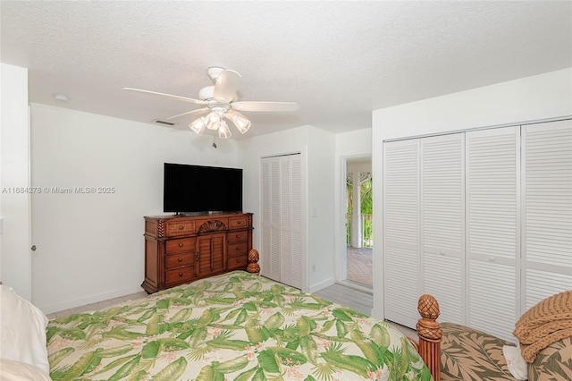 bedroom featuring ceiling fan, two closets, and a textured ceiling