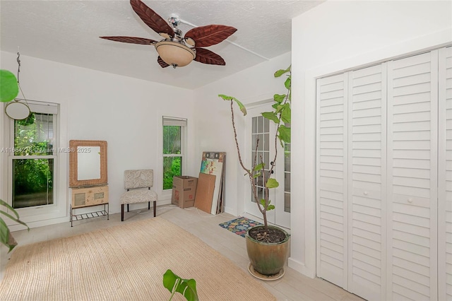 living area featuring a textured ceiling, ceiling fan, and plenty of natural light