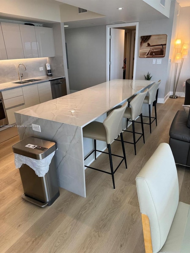 kitchen with a large island, light hardwood / wood-style flooring, sink, and white cabinets