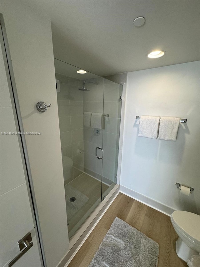 bathroom featuring a shower with shower door, wood-type flooring, and toilet