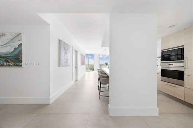 corridor with expansive windows and light tile patterned flooring