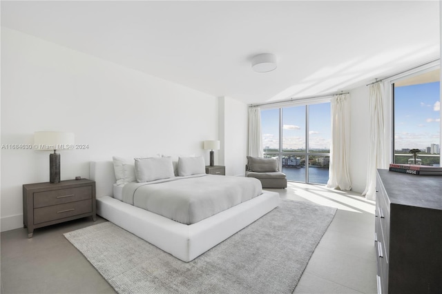 bedroom with a water view, access to exterior, and expansive windows