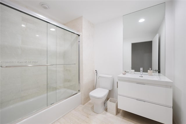 full bathroom with shower / bath combination with glass door, vanity, and toilet