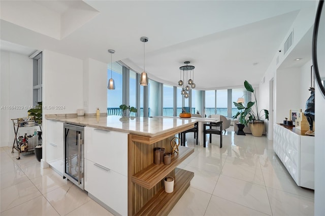 kitchen with white cabinets, pendant lighting, beverage cooler, and a notable chandelier