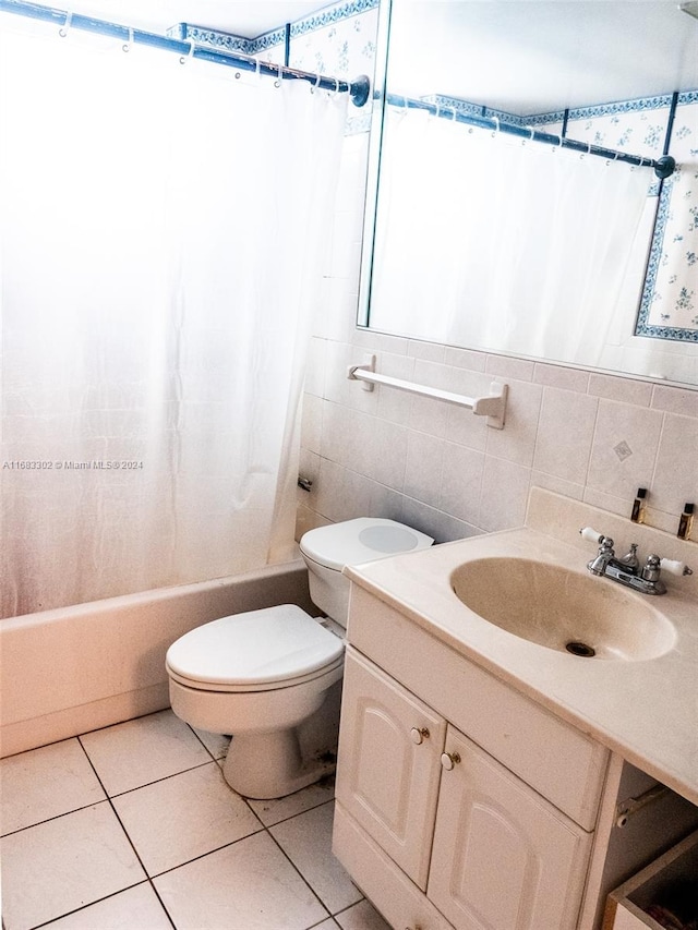 full bathroom with toilet, tile patterned floors, tile walls, vanity, and shower / tub combo with curtain