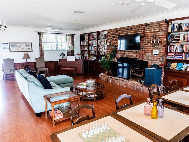 living room featuring a fireplace, wood-type flooring, and ceiling fan