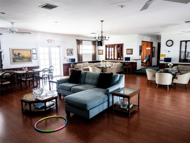 living room with ceiling fan with notable chandelier and dark hardwood / wood-style flooring