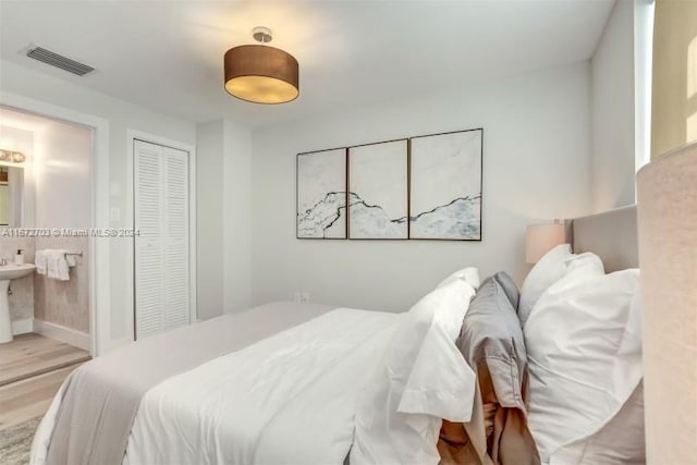 bedroom featuring light hardwood / wood-style floors, a closet, and ensuite bath