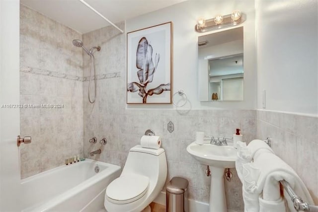 bathroom featuring toilet, tiled shower / bath combo, and tile walls