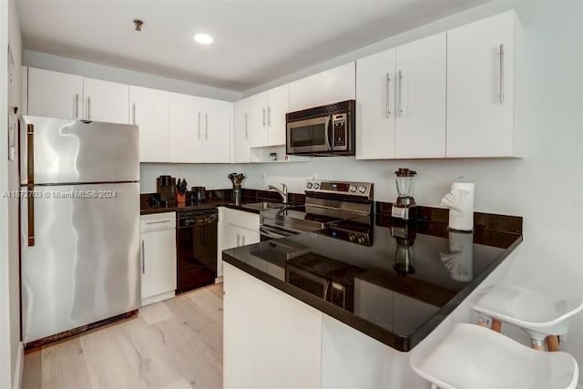 kitchen featuring kitchen peninsula, white cabinets, appliances with stainless steel finishes, light wood-type flooring, and sink